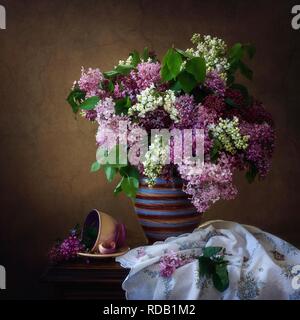 Still life with branches of lilac and a Cup of coffee on a wooden table ...