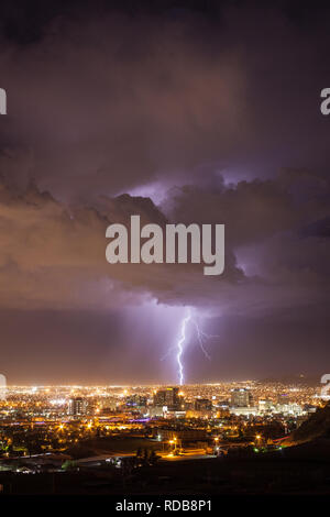 Lightning strikes the urban landscape behind the downtown El Paso, Texas skyline on a hot summer night near the US-Mexico border Stock Photo