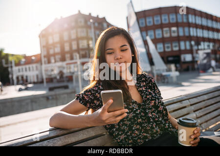 Young Asian college student sitting on campus using her cellphone Stock Photo