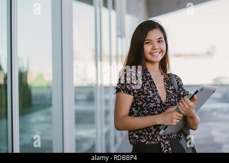 Young Asian university student smiling while standing on campus  Stock Photo
