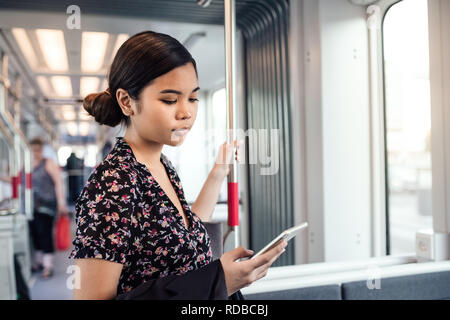 Young Asian student reading texts while riding the train Stock Photo