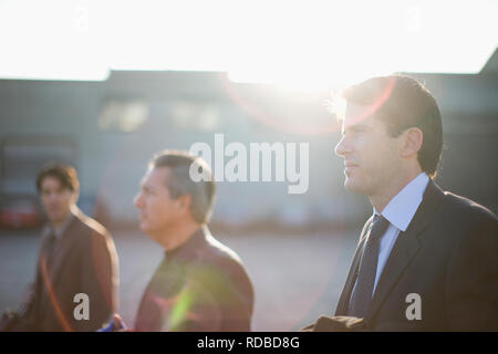 Three focused businessmen standing outside in the sun. Stock Photo