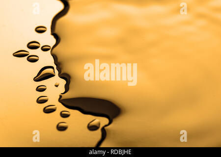 Golden water droplets on a shiny surface Stock Photo
