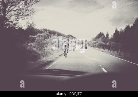 looking through car windscreen at cyclists on busy main road. A82 Fort William Scottish Highlands Scotland Britain UK Stock Photo