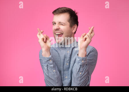 Hopeful young male crosses fingers before having job interview, worries much, wish good luck Stock Photo