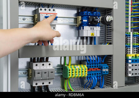 hand pointing towards fuse in a fuse box - electrical and instrumentation works Stock Photo