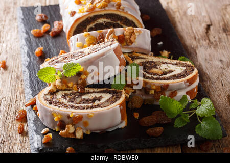 Festive glazed poppy beigli cake with raisins, walnuts close-up on a wooden table. horizontal Stock Photo