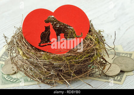 Cat and dog silhouette cut out in paper heart in a nest on money - Concept of pet shelter donations Stock Photo