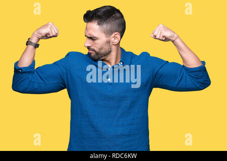 Young handsome man over isolated background showing arms muscles smiling proud. Fitness concept. Stock Photo