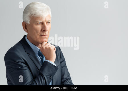 Business Lifestyle. Businessman standing isolated on gray touching chin thoughtful Stock Photo