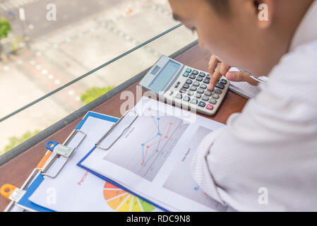 Businessman checking financial number on reports with calculator Stock Photo