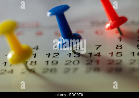 Embroidered blue pins on a calendar on the 13rd with selective focus Stock Photo