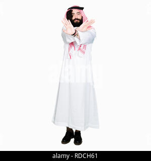 Arabian business man with long hair wearing traditional keffiyeh scarf Rejection expression crossing arms and palms doing negative sign, angry face Stock Photo