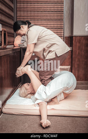Skilled nice Asian masseuse doing Thai massage Stock Photo