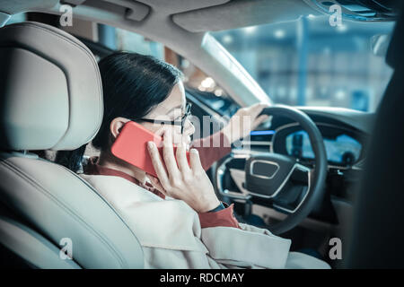 Dark-haired woman calling her children while driving home Stock Photo