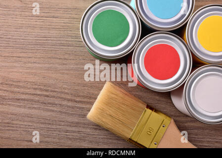 Paint pots and brush on brown wooden table with light effect. Horizontal composition. Top view. Stock Photo