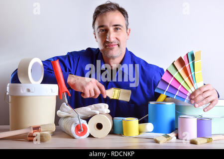 Smiling worker presenting painting tools and products on table. Horizontal composition. Front view. Stock Photo