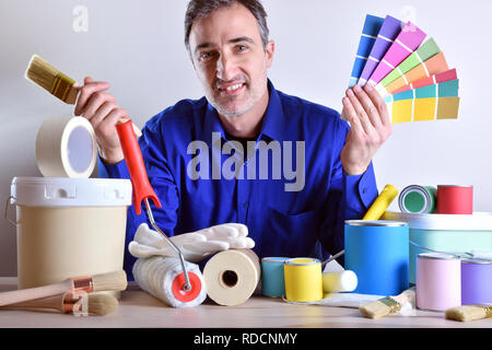 Smiling worker presenting painting tools on table. Horizontal composition. Front view. Stock Photo