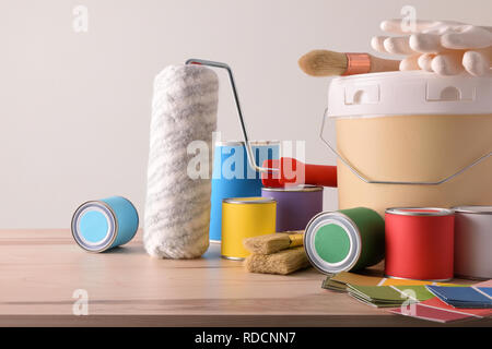 Wooden table with material and painting tools for home and white wall background. Horizontal composition. Front view. Stock Photo