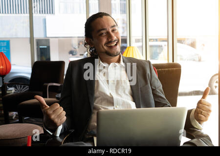 young indian business male on laptop, phone and coffee at a cafe Stock Photo