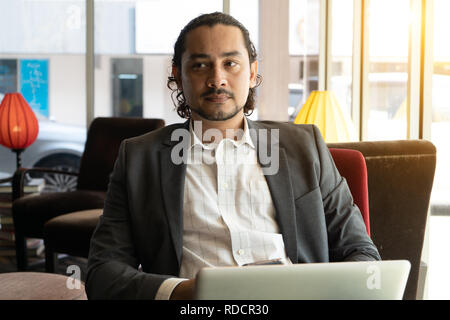young indian business male on laptop, phone and coffee at a cafe Stock Photo