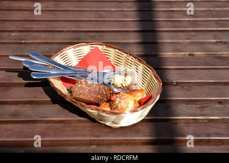 Basket with bread and cutlery on brown wooden table. Selective focus. Stock Photo