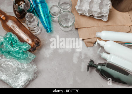 Differnt types of waste, plastic bag, crumpled paper, plastic containers, glass and bottles on the table. Management waste sorting concept Stock Photo