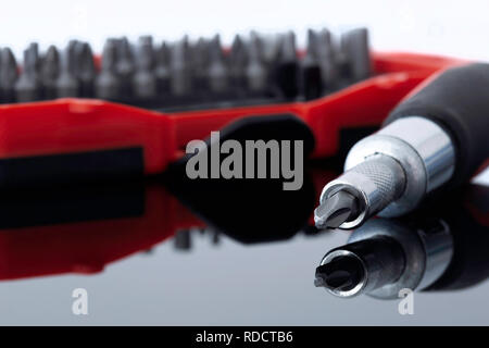 Screwdriver with phillips head with various bits in a case in the background reflected on a glass surface Stock Photo
