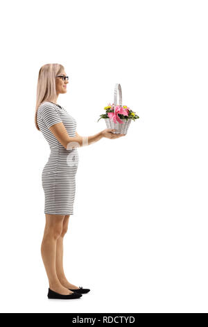 Full length profile shot of a young woman holding a basket with flowers isolated on white background Stock Photo