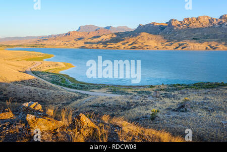 View across the rugged undulating landscape of Shoshone river/reservoir  flanked by prairie and Rocky Mountains, Cody, Wyoming, USA. Stock Photo