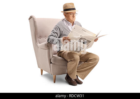 Senior man sitting in an armchair and reading a newspaper isolated on white background Stock Photo