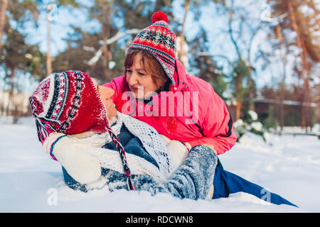 Senior couple hugging in winter forest. Man and woman lying in snow and having fun on Valentine's Day outdoors Stock Photo