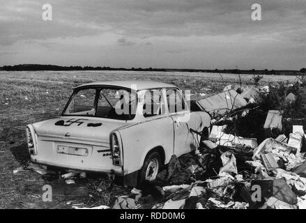 GERMANY in 1990 after reunification, former East Germany, German Democratic Republic GDR, typical plastic car Trabant also called Trabbi with fascist Nazi symbol swastika Hakenkreuz on wild dumping site in village Plauerhagen, Mecklenburg, people have dumped their East German car in exchange to new western cars, scan from black and white negative with film grain Stock Photo