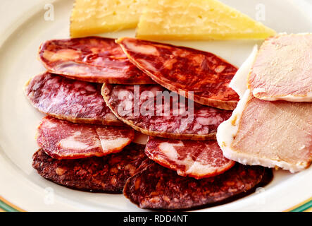 A typical selection of Iberico cold meats includes ham (Jamon), cured loin of pork (lomo), Spanish red sausage (chorizo) and salchichón. Stock Photo