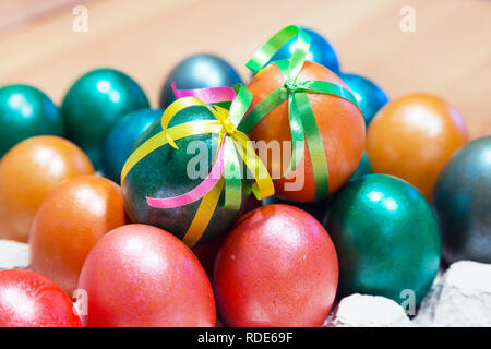 Brightly colored bow decorated easter eggs in egg carton holder, holiday background Stock Photo