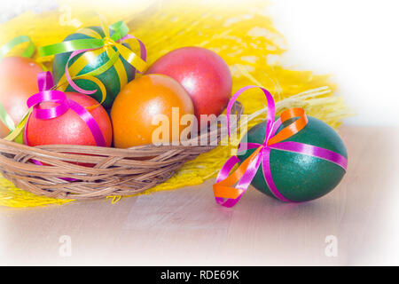 Brightly colored bow decorated easter eggs in basket, holiday background Stock Photo