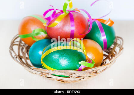 Brightly colored bow decorated easter eggs in basket, holiday background Stock Photo