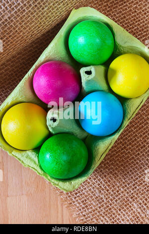 Brightly colored bow decorated easter eggs in egg carton holder, holiday background Stock Photo