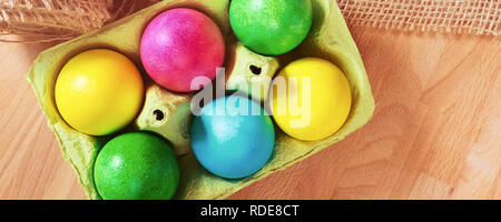 Brightly colored bow decorated easter eggs in egg carton holder, banner background Stock Photo