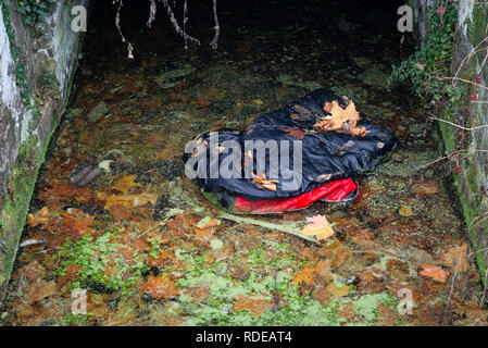 A discarded sleeping bag in a weir in Waltham Abbey, Essex Stock Photo