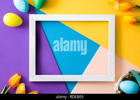 Easter concept.wooden empty frame with easter eggs and tulips on colorful background Stock Photo
