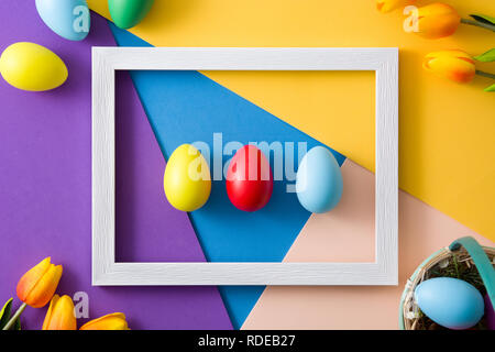 Easter concept.wooden frame with easter eggs and tulips on colorful background Stock Photo