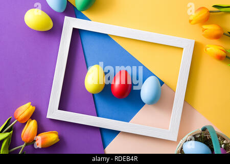 Easter concept.wooden frame with easter eggs and tulips on colorful background Stock Photo