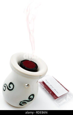 Dragon's blood powder in charcoal disc placed in oil burner on the white background Stock Photo