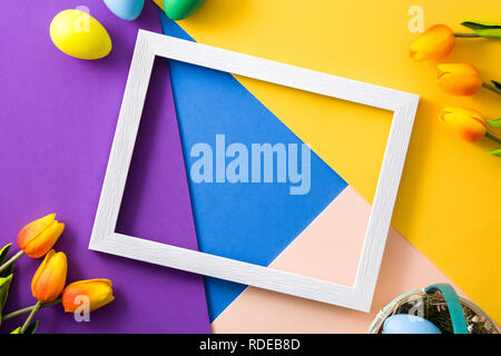 Easter concept.wooden empty frame with easter eggs and tulips on colorful background Stock Photo