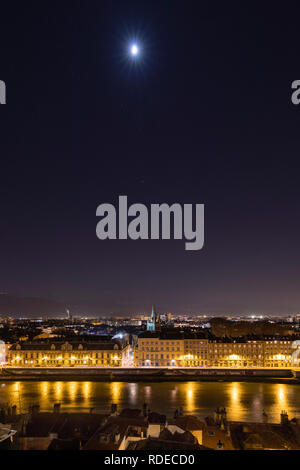 Grenoble, France, January 2019 : City at night with isere river, the moon and stars in the sky. Stock Photo
