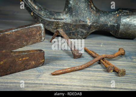 Old rusty nails with two claw hammers in a close up cropped view in a maintenance, repair, construction or DIY concept Stock Photo