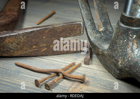 Old rusty nails with two claw hammers in a close up cropped view in a maintenance, repair, construction or DIY concept Stock Photo