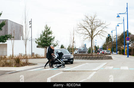 STRASBOURG, FRANCE - APR 2, 2018: female couple crossing street pushing stroller car letting them pass Stock Photo