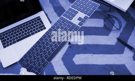 LONDON, UNITED KINGDOM - APR 15, 2018: Man pov unboxing installing charging connecting to Apple MacBook pro retina laptop 15 inch to new Magic Keyboard with Numeric Keypad Space Gray - blue technological background Stock Photo